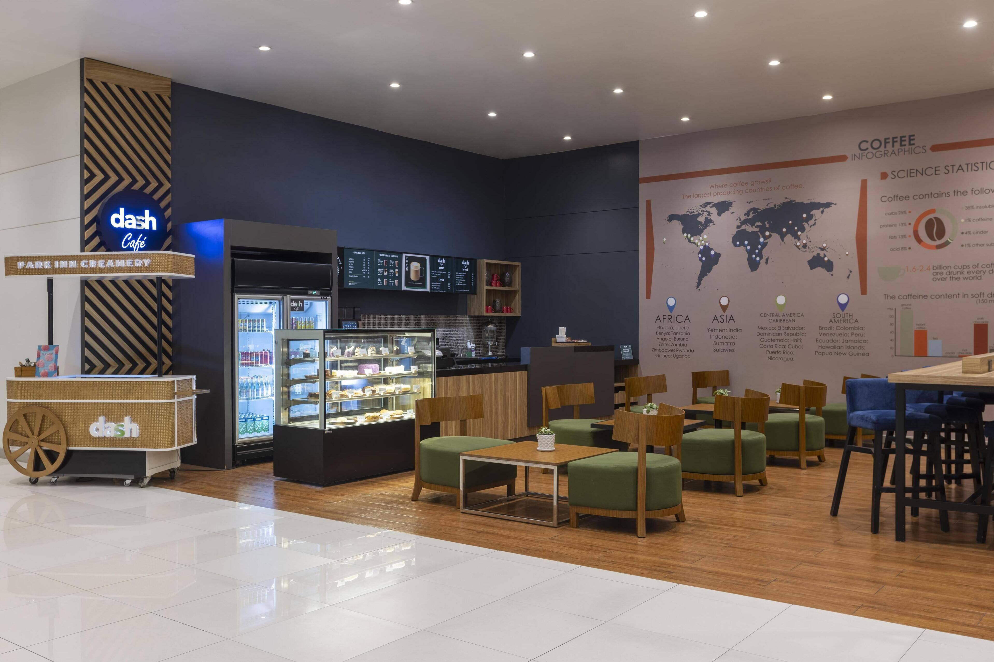 A modern cafe interior with a coffee display, seating area, and informational posters.