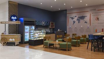 A modern cafe interior with a coffee display, seating area, and informational posters.