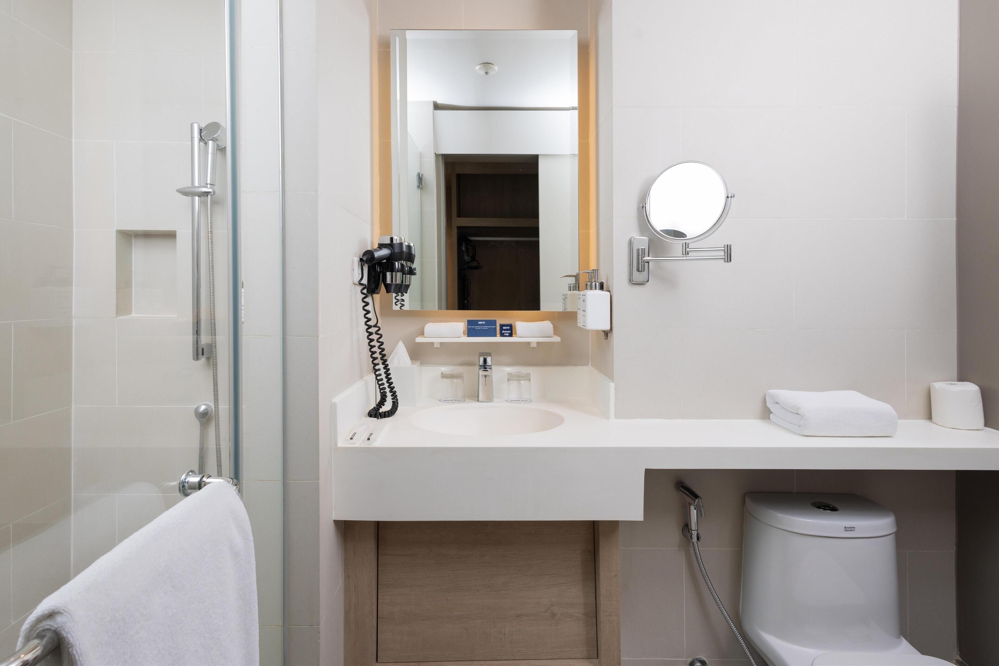 A modern bathroom with a glass-enclosed shower, a sink with a mirror above, and a toilet with a bidet attachment.