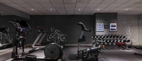 Un gimnasio con cintas de correr, elíptica y banco de pesas.