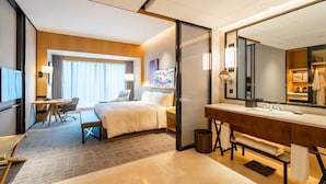 A hotel room with a bed, desk, chair, and a large mirror. - Radisson Hangzhou Qianjiang (Hangzhou)