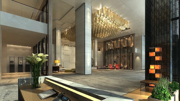 A modern lobby with a reception desk, a phone, a vase with flowers, and a seating area with chairs and a red sofa. - Radisson Hangzhou Qianjiang (Hangzhou)