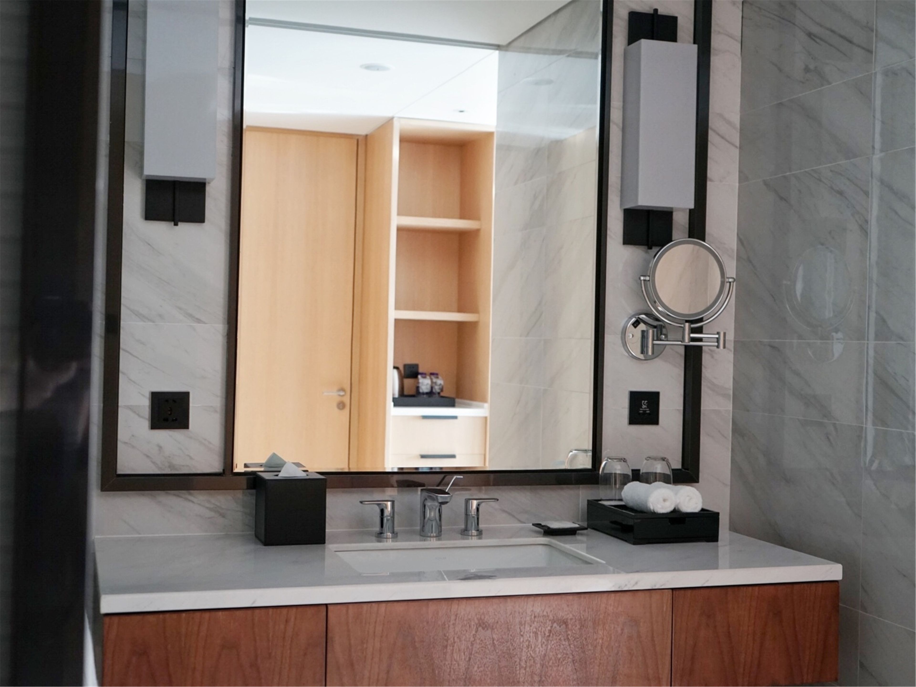 Un baño moderno con un espejo grande, un lavabo doble y un mueble de tocador de madera.