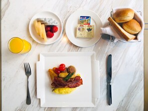 Enjoy a hearty breakfast with scrambled eggs, fresh fruit, and warm bread rolls.
