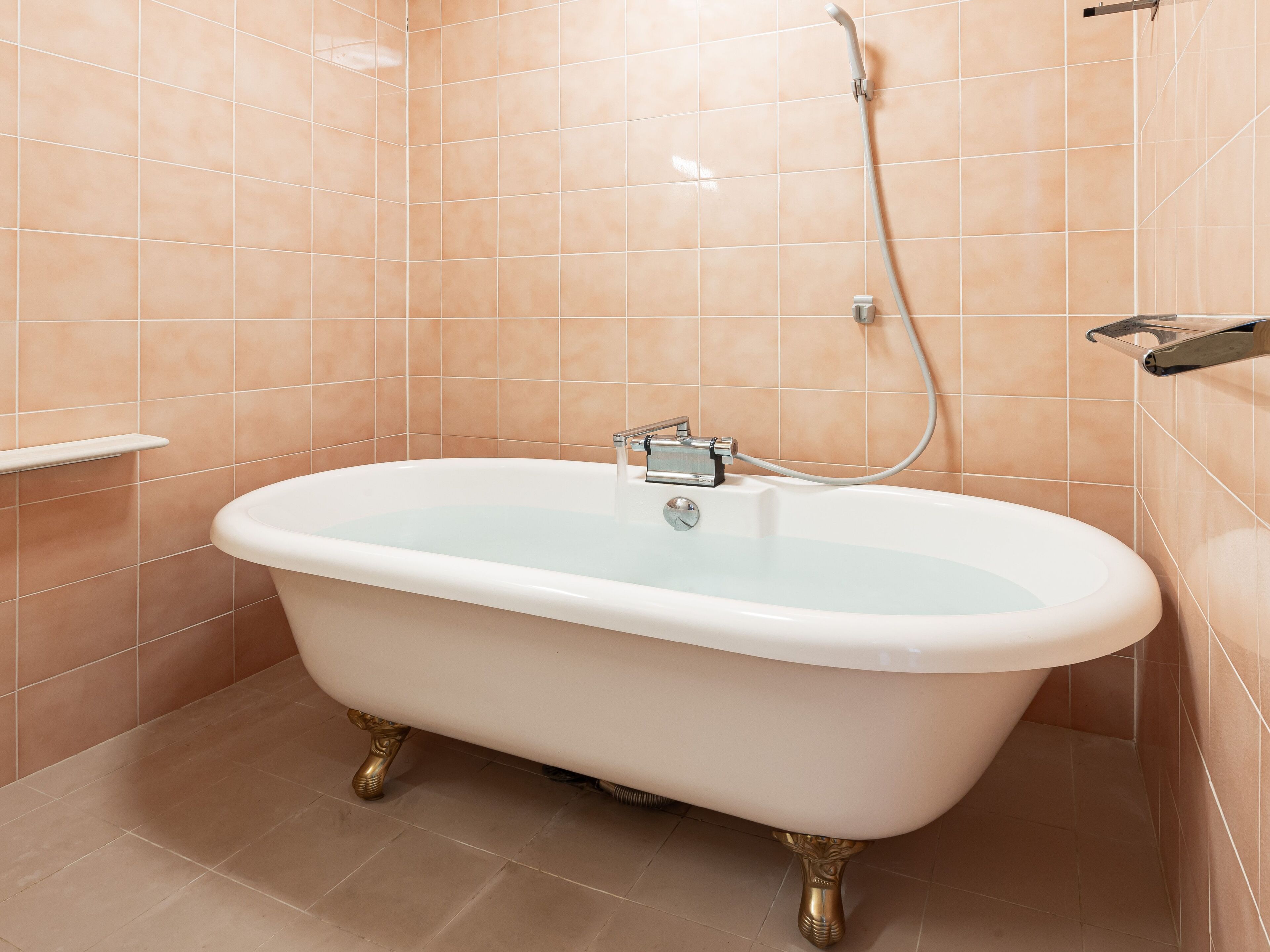 A bathroom with a freestanding bathtub, a showerhead, and a towel rack.