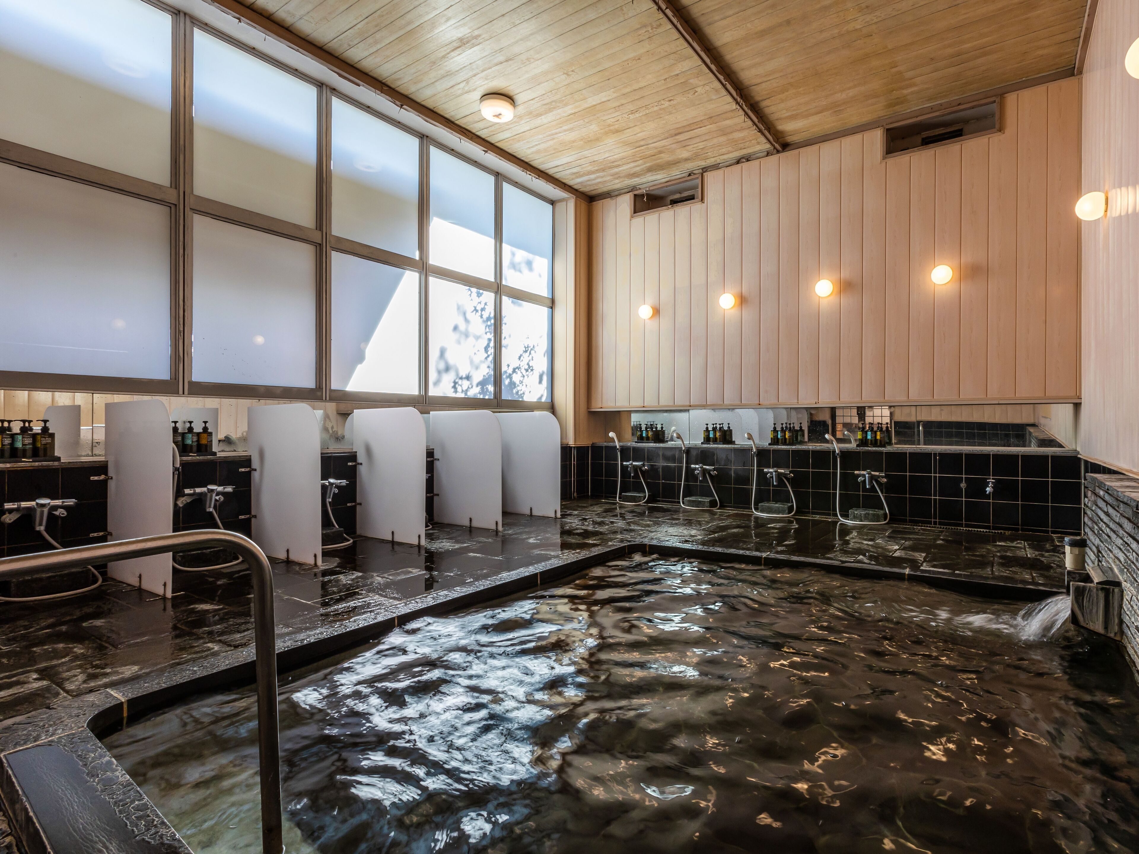 A spa area with multiple hot tubs, wooden paneling, and a tiled floor.