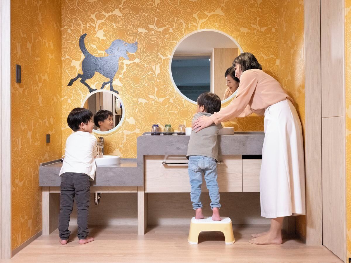 Un baño con lavamanos doble, espejo y decoración en la pared.