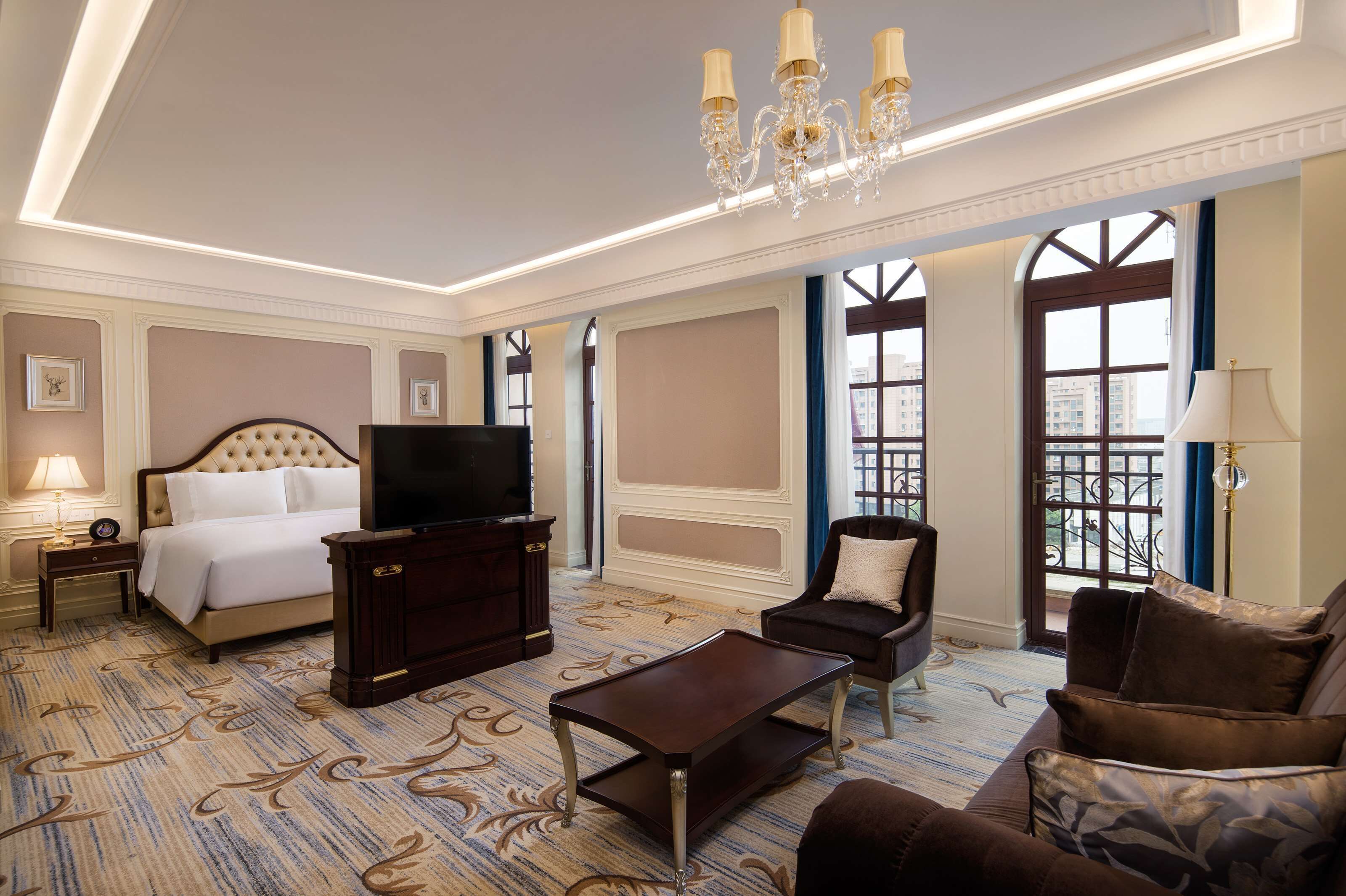 A hotel room with a bed, a TV, a desk, a chair, and a sofa.