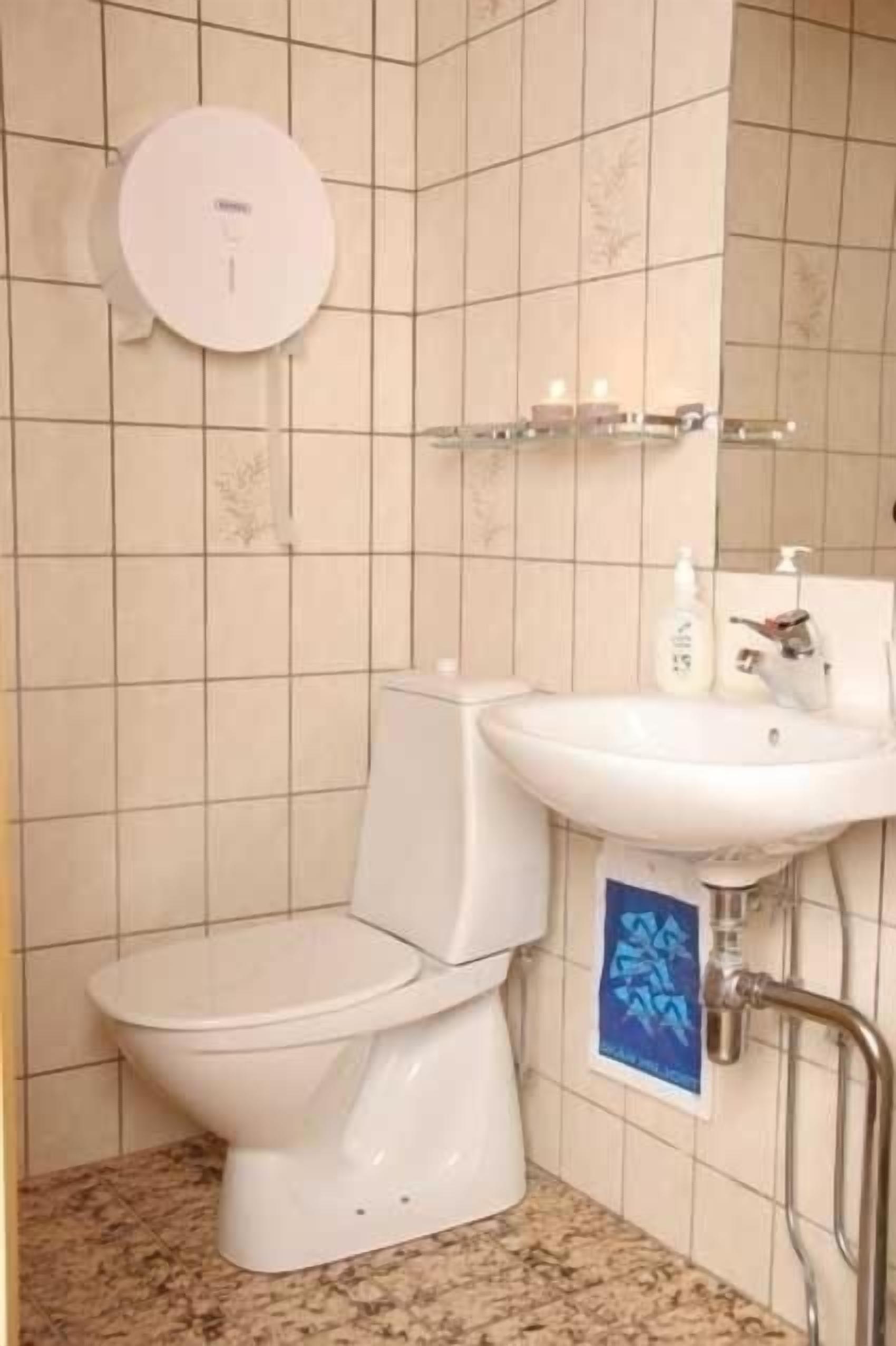 A bathroom with a toilet, sink, and a hand dryer mounted on the wall.