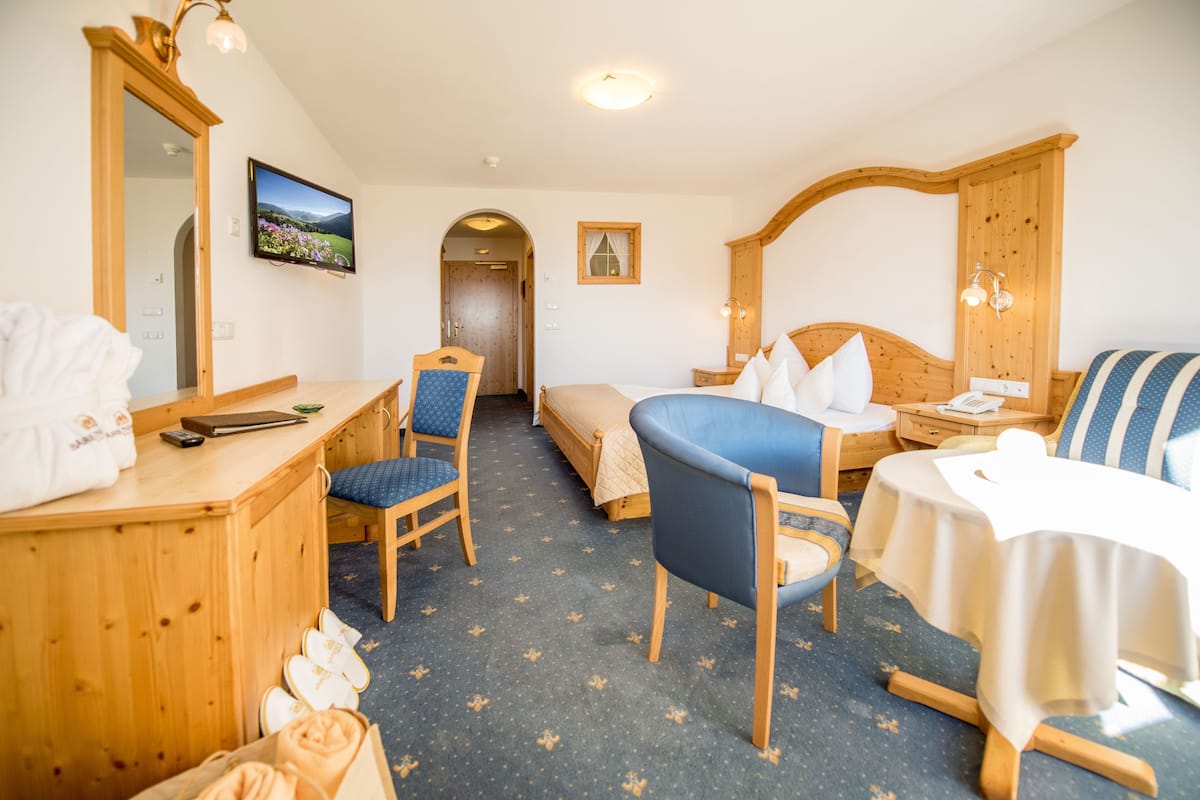 A hotel room with a bed, a desk, a chair, a table, and a television.