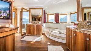 Un baño lujoso con tocador de madera, un espejo grande y vistas a la montaña.