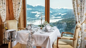 Mesa para dos preparada con vistas a la montaña, una vela y un jarrón con flores.