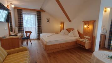 Ein Schlafzimmer mit einem hölzernen Bett, einem Schreibtisch, einem Stuhl und einem an der Wand befestigten Fernseher.