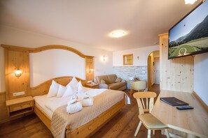 Un dormitorio con una cama de madera, un sofá, un escritorio y un televisor que muestra una vista panorámica.
