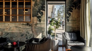 A modern interior with a large window, a potted plant, and leather seating.