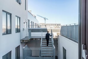 A person descending a metal staircase in a modern building with large windows and a construction crane in the background.