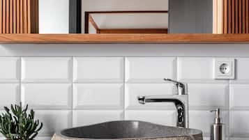 A modern bathroom with a stone sink, wooden paneling, and a mirror above.