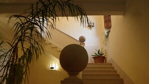 A staircase with a balustrade, a potted plant, and a wall-mounted light fixture. - Casa Laino (Belcastro)