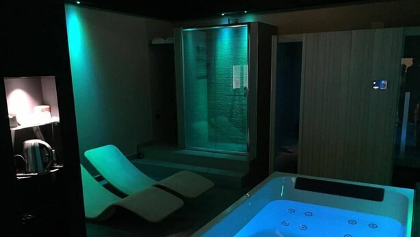 A modern spa room with a heated tub, a massage chair, and a glass-enclosed steam shower. - Casa Laino (Belcastro)