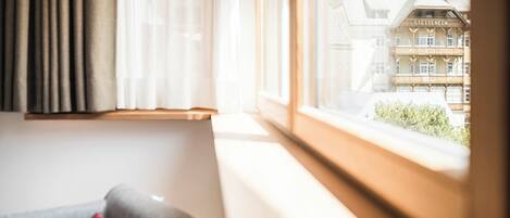 A room with a window overlooking a building with a balcony.