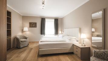 Quarto de hotel com uma cama, duas mesas de cabeceira, uma cadeira, um guarda-roupa e um espelho grande.