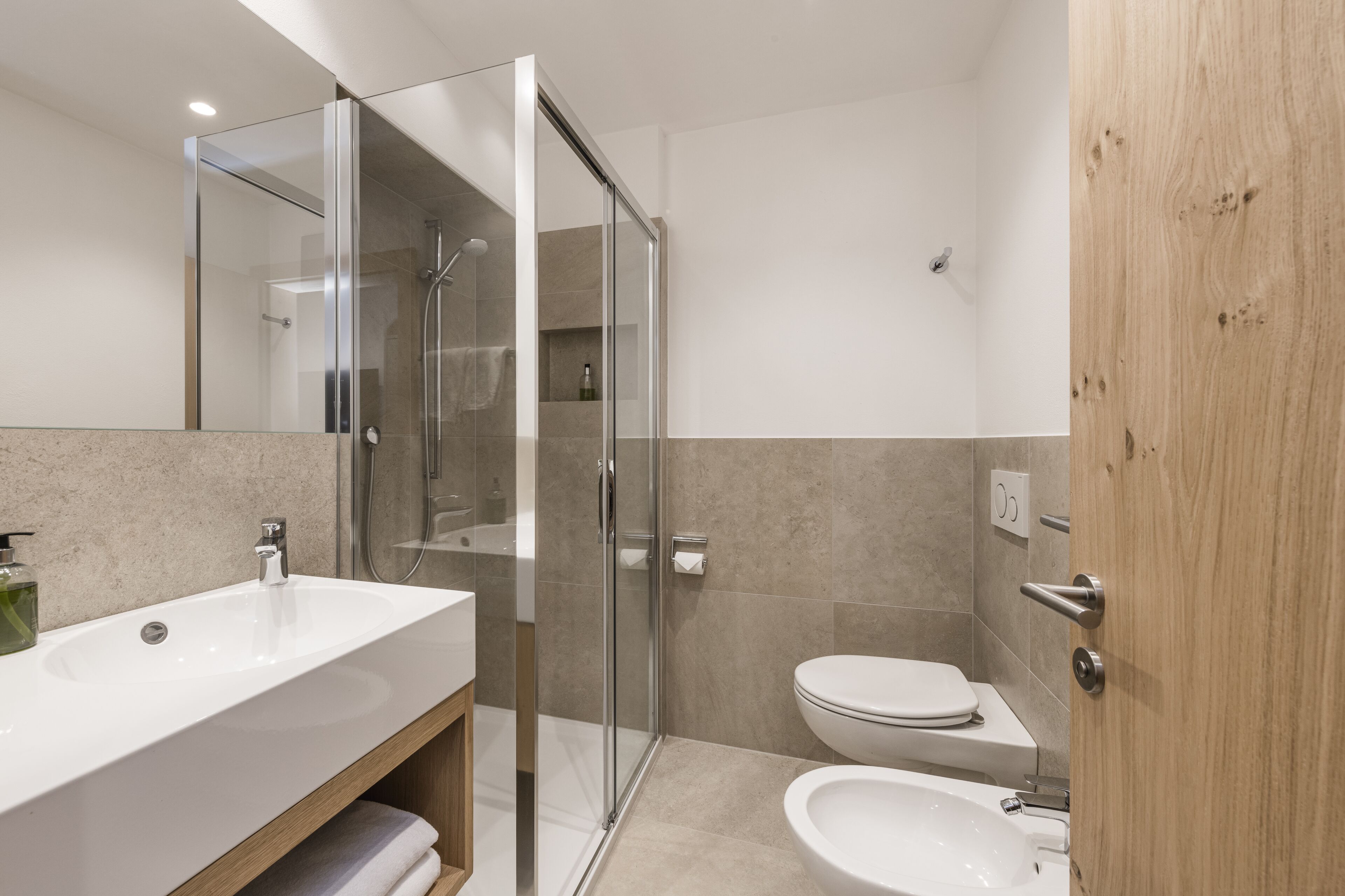 A modern bathroom with a glass shower enclosure, a white sink, and a toilet.