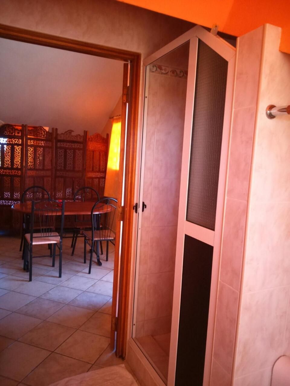 Una habitación con puerta corrediza que da a un comedor con mesa y sillas.