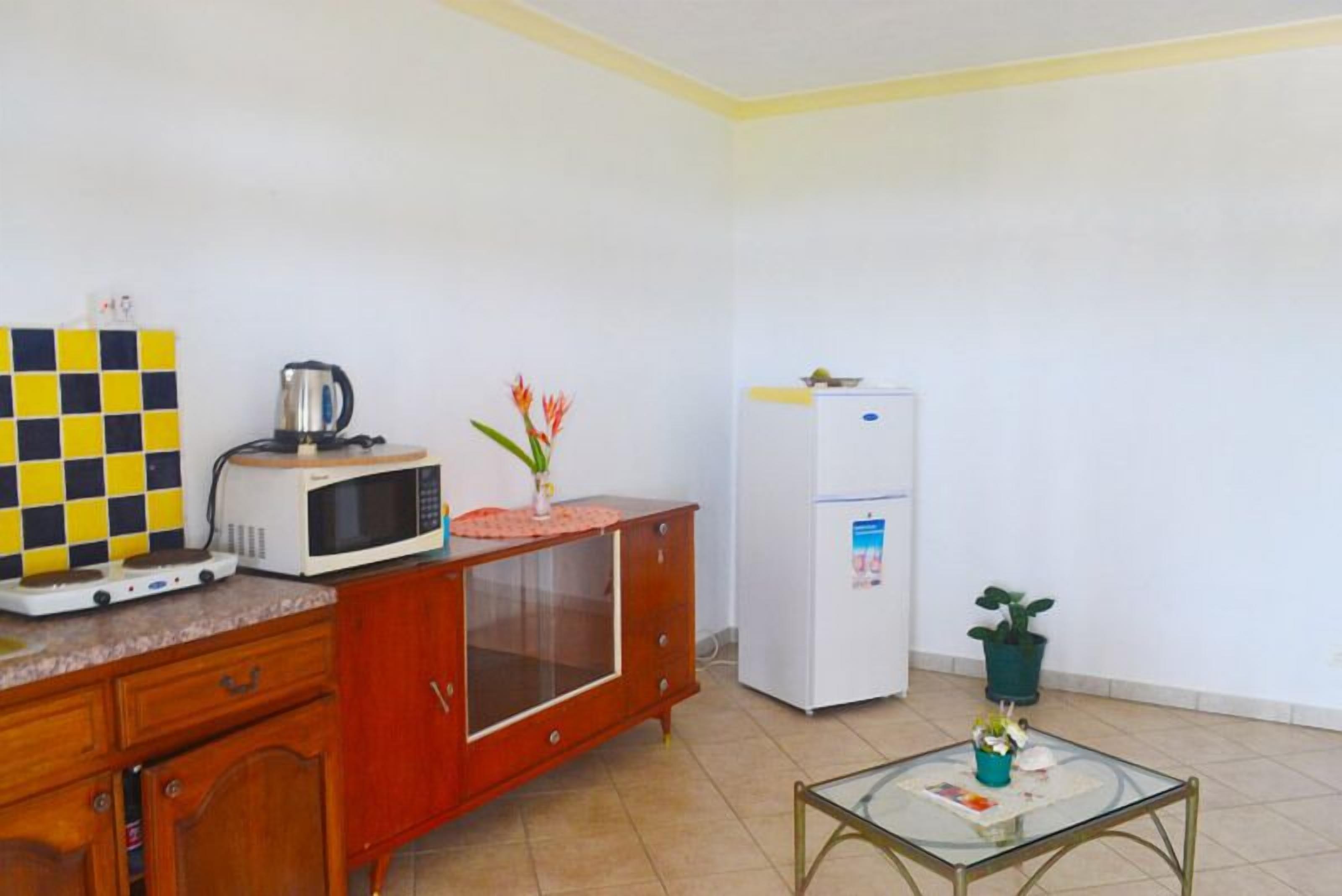 Uma cozinha compacta equipada com micro-ondas, torradeira e frigorífico.