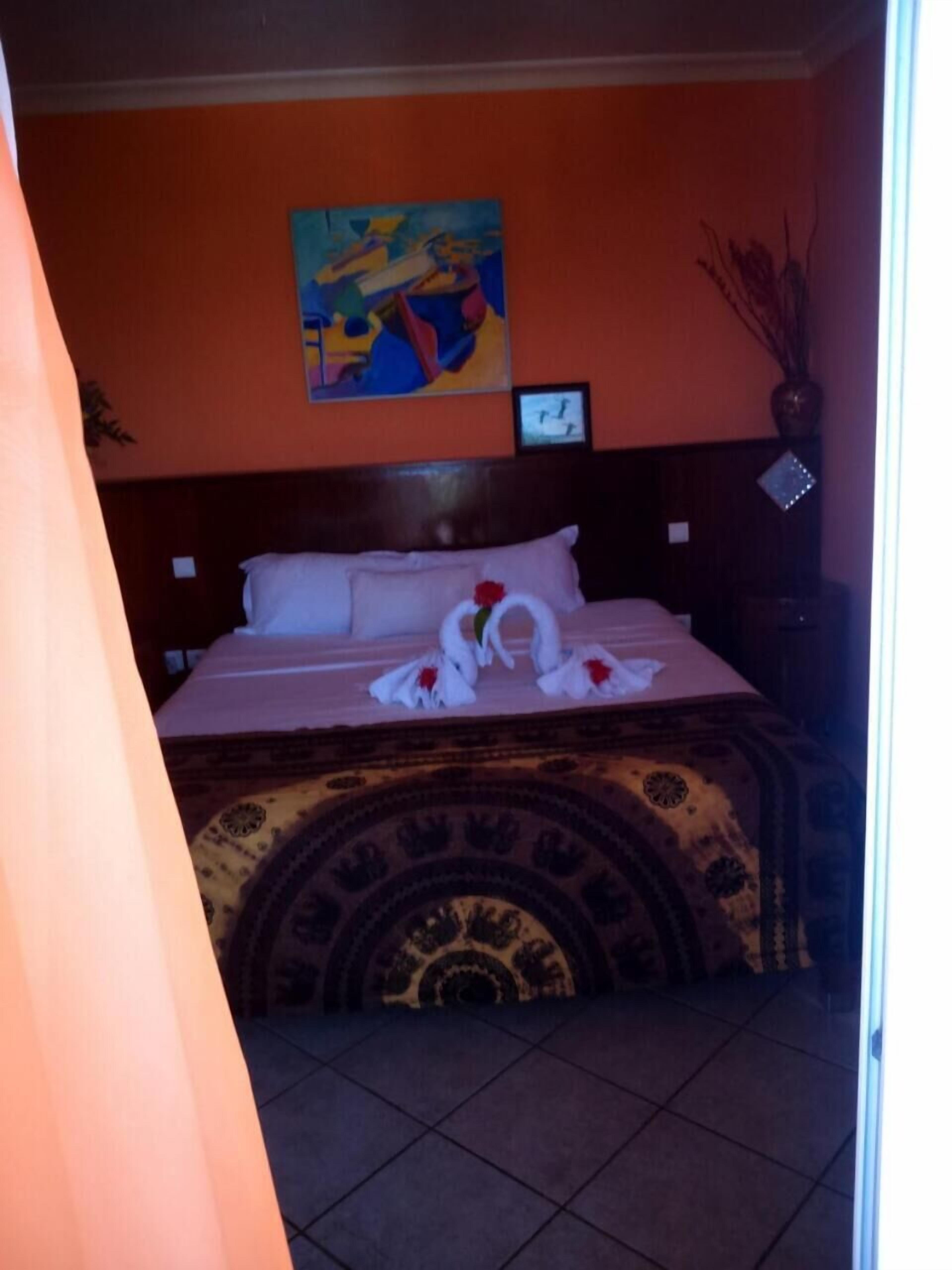 Una habitación de hotel con una cama, un cuadro en la pared y un reloj.