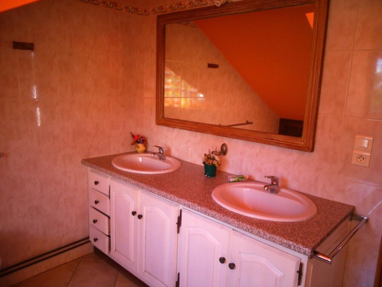 Un baño con dos lavamanos, un espejo y un mueble con cajones.