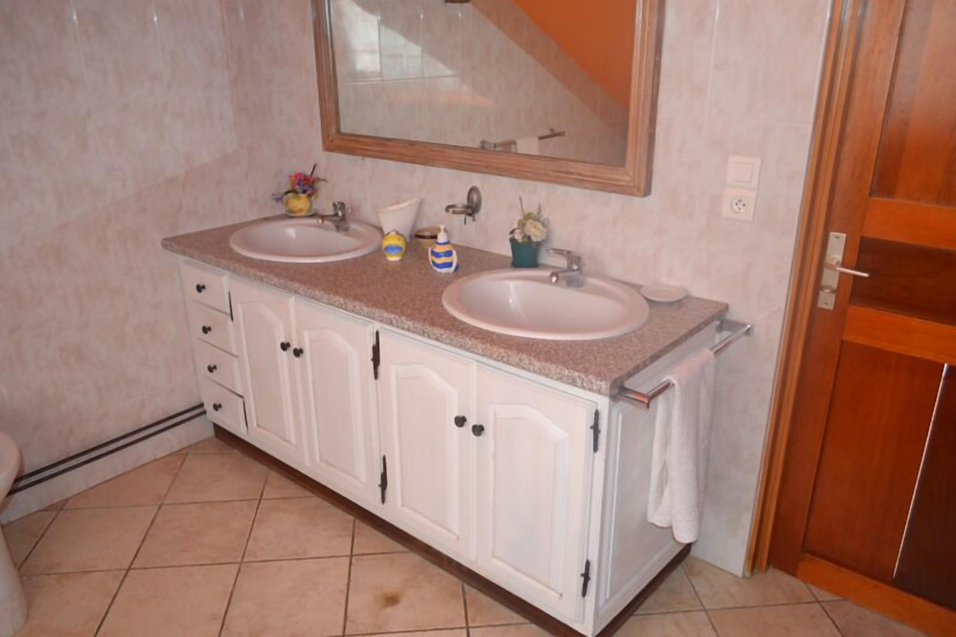 A bathroom with two sinks, a mirror, and a cabinet with drawers.
