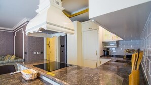 A modern kitchen with a central island, white cabinetry, and a backsplash of blue tiles. - Alanya Towers C Blok (Alanya)
