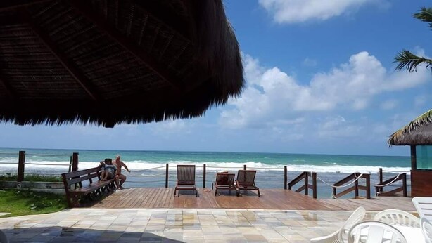 Eine Strandterrasse mit Holzstühlen und einem Strohdach.