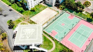 Eine Luftaufnahme eines Sportkomplexes mit Basketballfeld, Tennisplatz und einem überdachten Bereich mit großem EV-Logo.