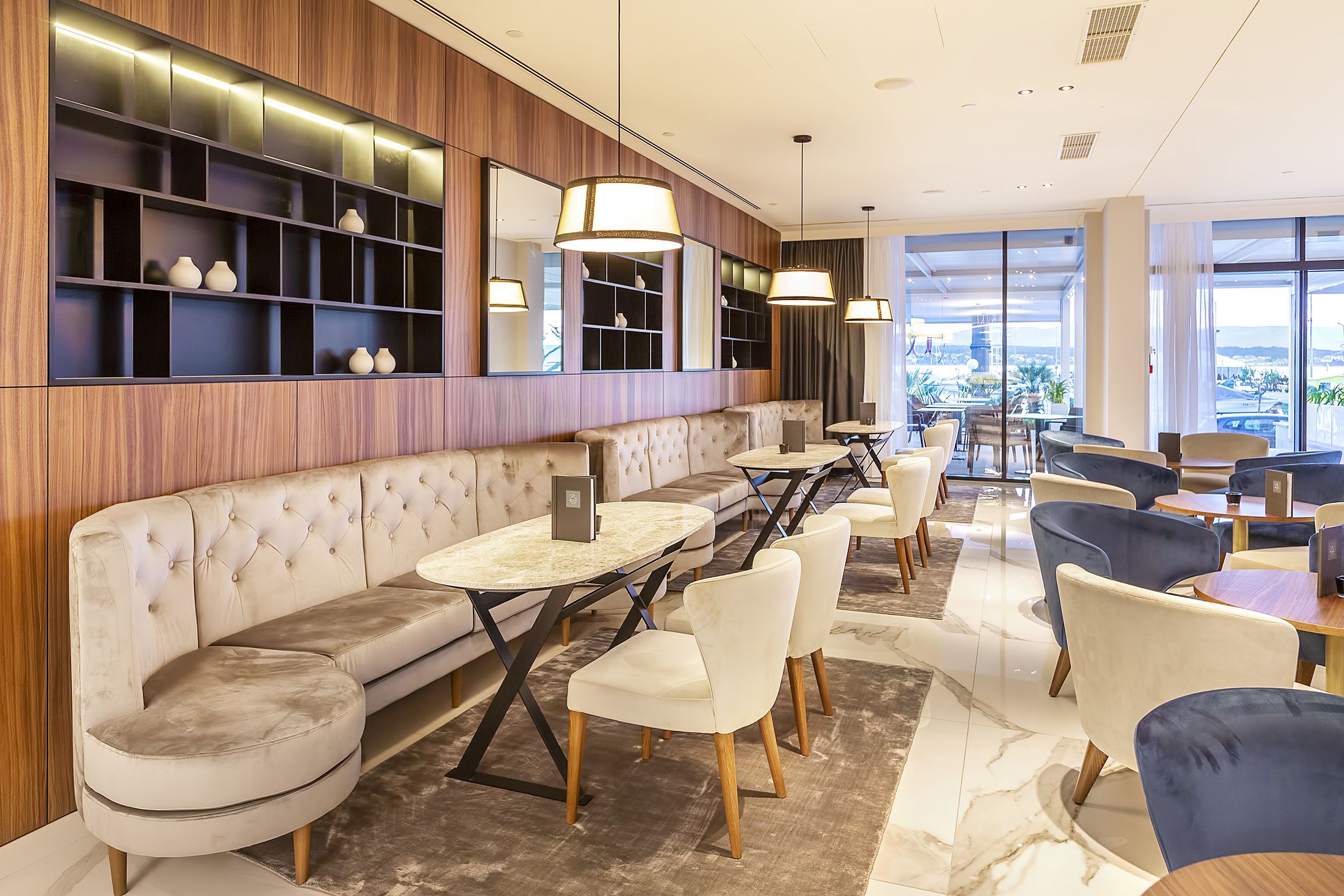 Eine moderne Hotelhalle mit Sitzgelegenheiten, einer Bar und großen Fenstern mit Blick auf die Stadt.