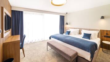 Una habitación de hotel moderna con una cama grande, un escritorio, un banco y un televisor.