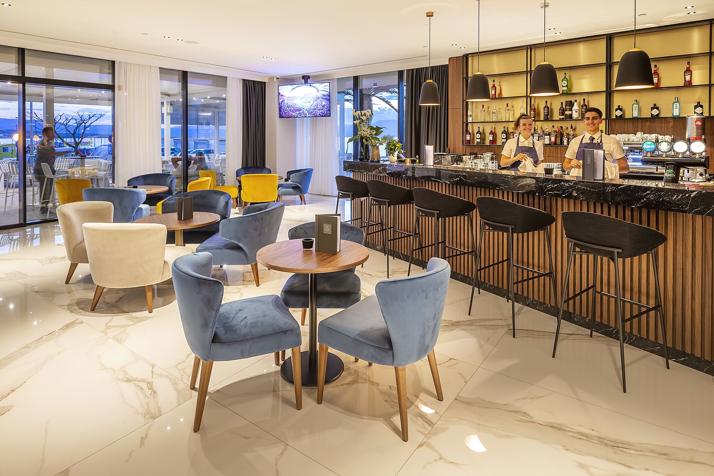 A modern bar area with seating, a bar counter, and a television screen.