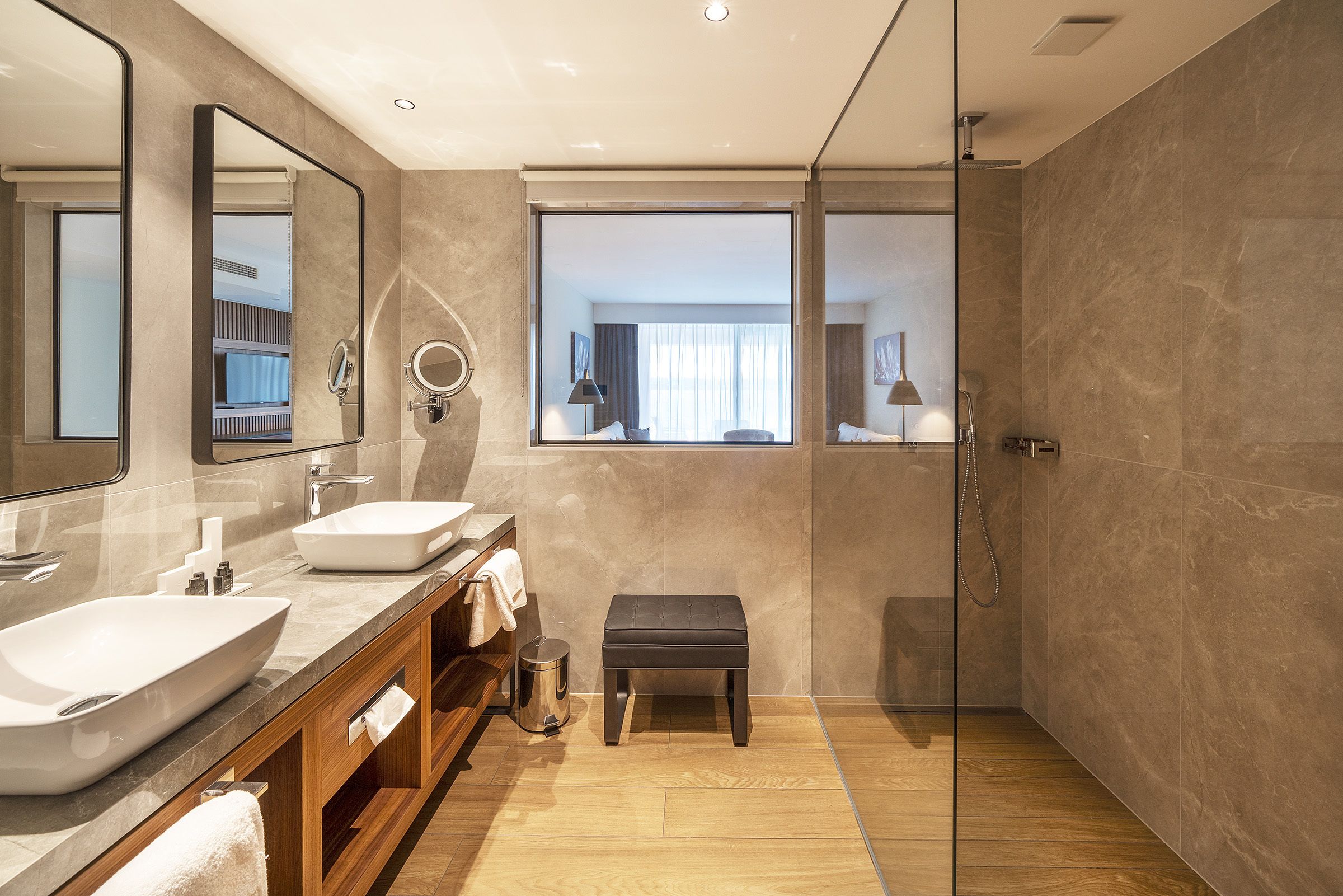 Un baño moderno con un espejo grande, dos lavamanos, tocador y zona de ducha.