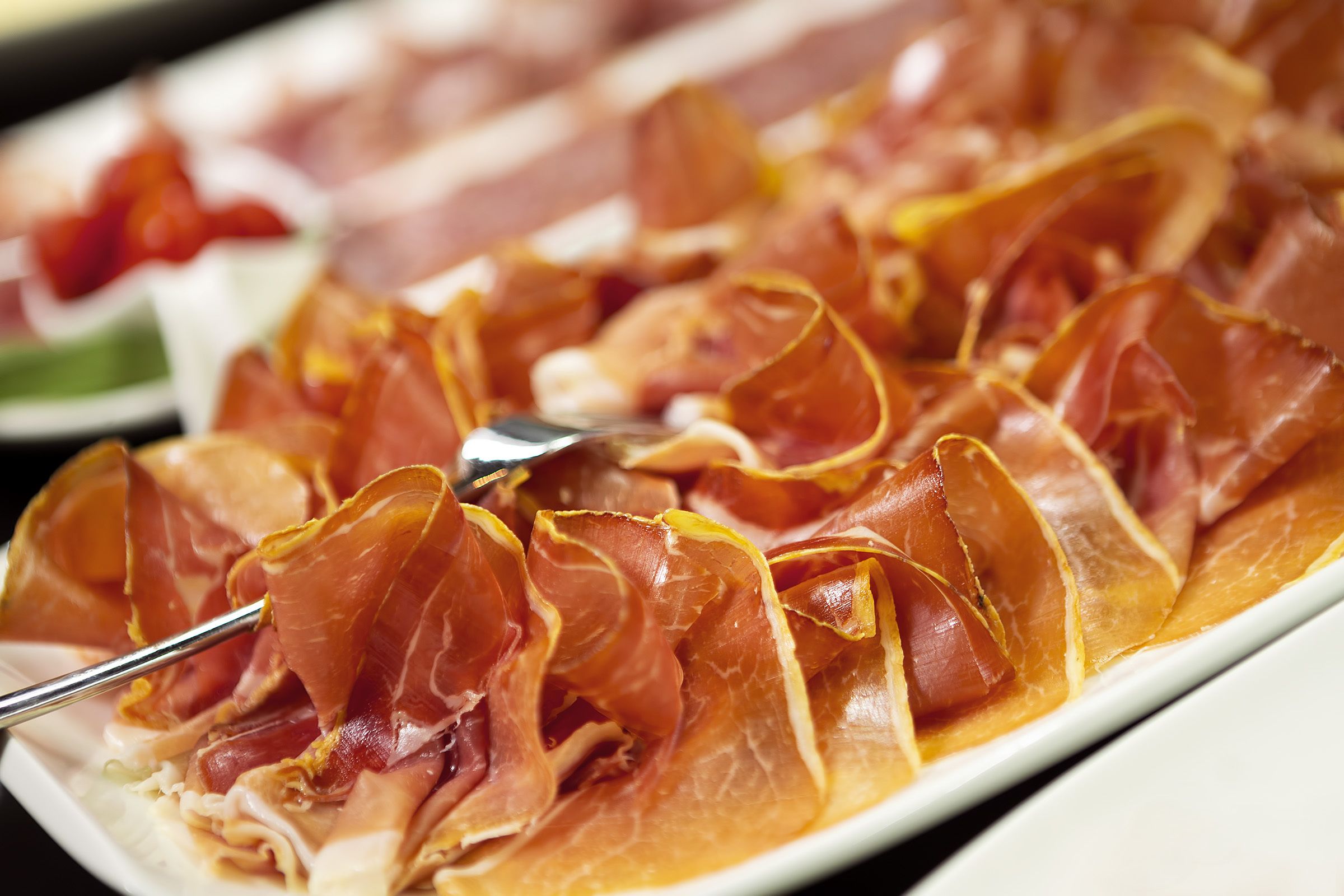 A plate of thinly sliced cured meat arranged in a fan shape.