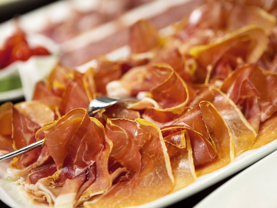 A plate of thinly sliced cured meat arranged in a fan shape.
