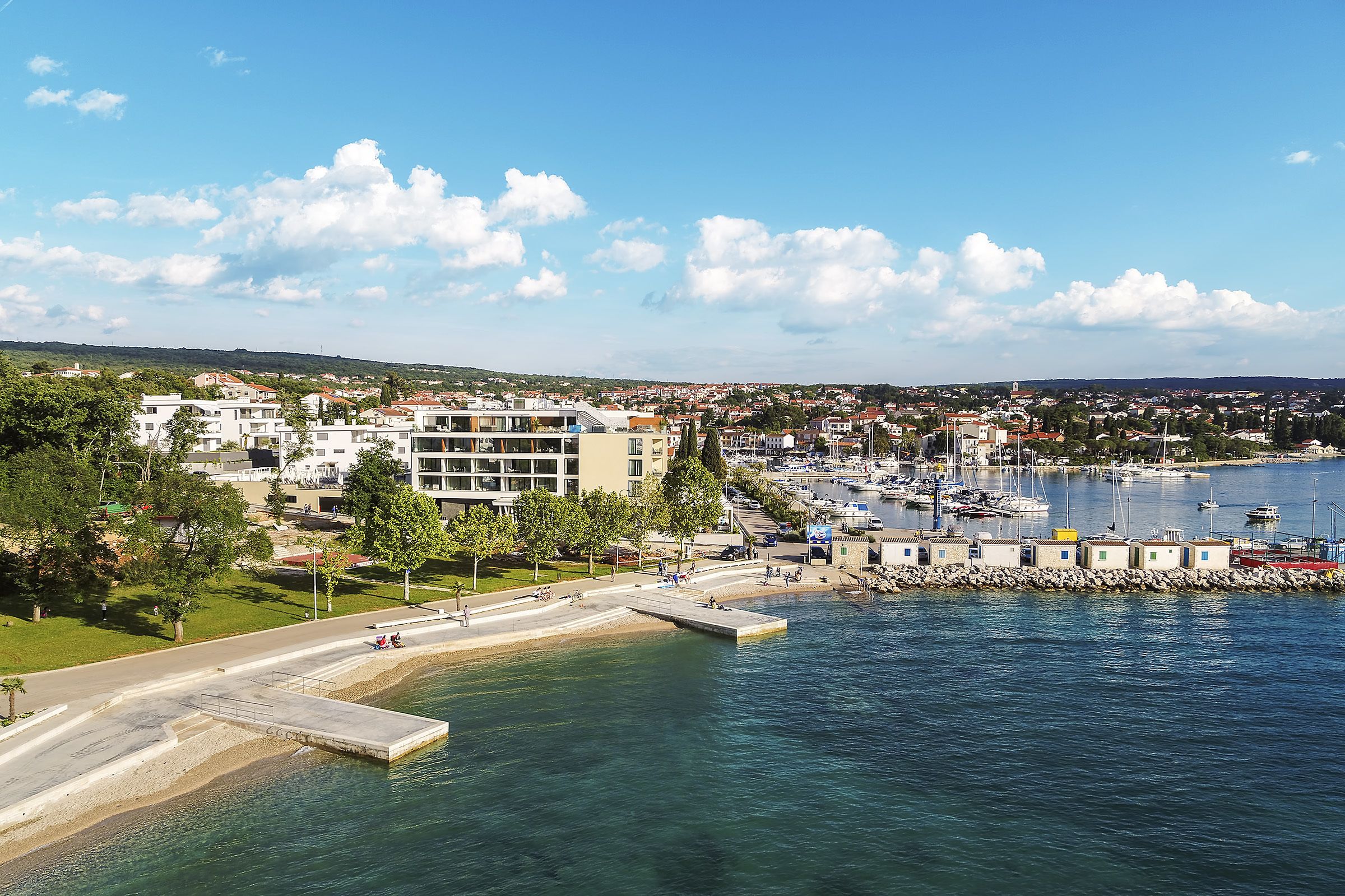 A coastal town with a marina, buildings, and a waterfront promenade.
