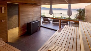 A balcony with wooden flooring, a seating area with chairs and a table, a grill, and a view of the sea. - Hotel Riva (Malinska-Dubasnica)