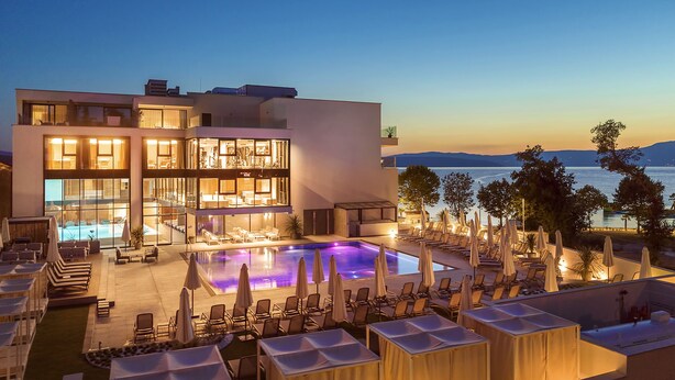 A modern hotel with a pool area, lounge chairs, and umbrellas. - Hotel Riva (Malinska-Dubasnica)