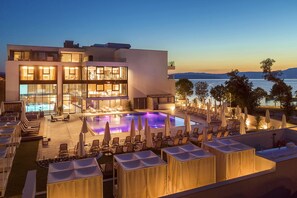 A modern hotel with a pool area, lounge chairs, and umbrellas. - Hotel Riva (Malinska-Dubasnica)