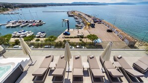 A marina with boats, a parking area, and sun loungers with umbrellas. - Hotel Riva (Malinska-Dubasnica)