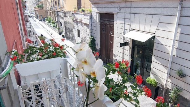 Eine enge Straße mit Balkonen, verziert mit roten Blumen und weißen Orchideen.