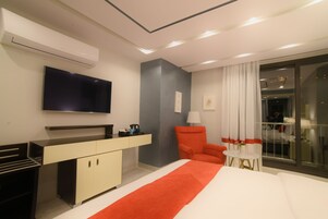 Una habitación de hotel moderna con cama, escritorio, silla, televisión y balcón con vistas.