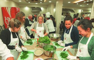 Un grupo de personas en una cocina preparando comida, con un refrigerador de Coca-Cola al fondo.