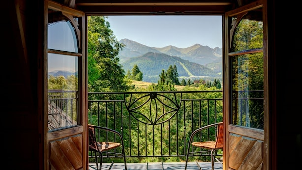 Een balkon met uitzicht op bergen en bomen.