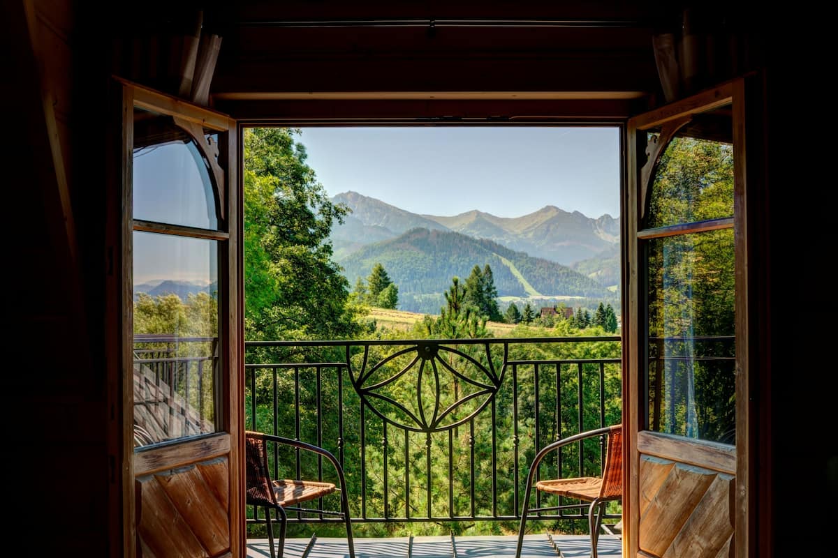 A balcony with a view of mountains and trees.